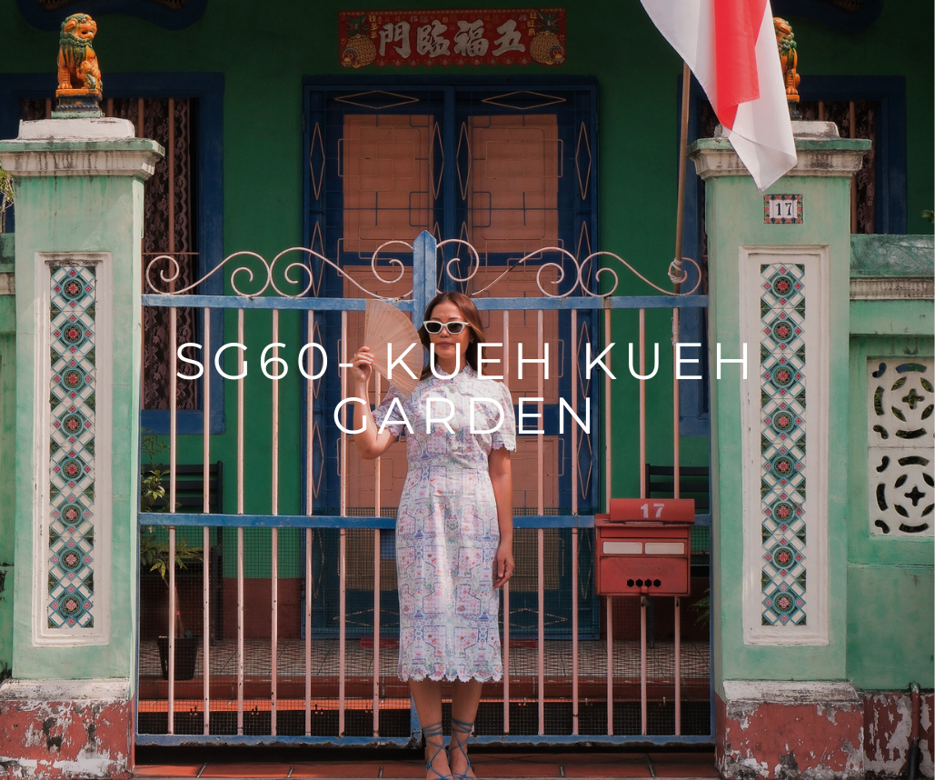 Woman in patterned dress holding a fan, standing in front of a colorful Peranakan-style house with text “SG60 Kueh Kueh Garden” overlay